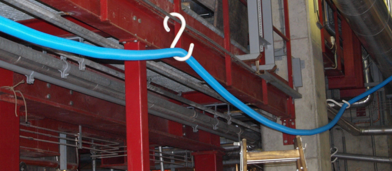 Hvid S-formet kabelkrog holder kabel på industrianlæg