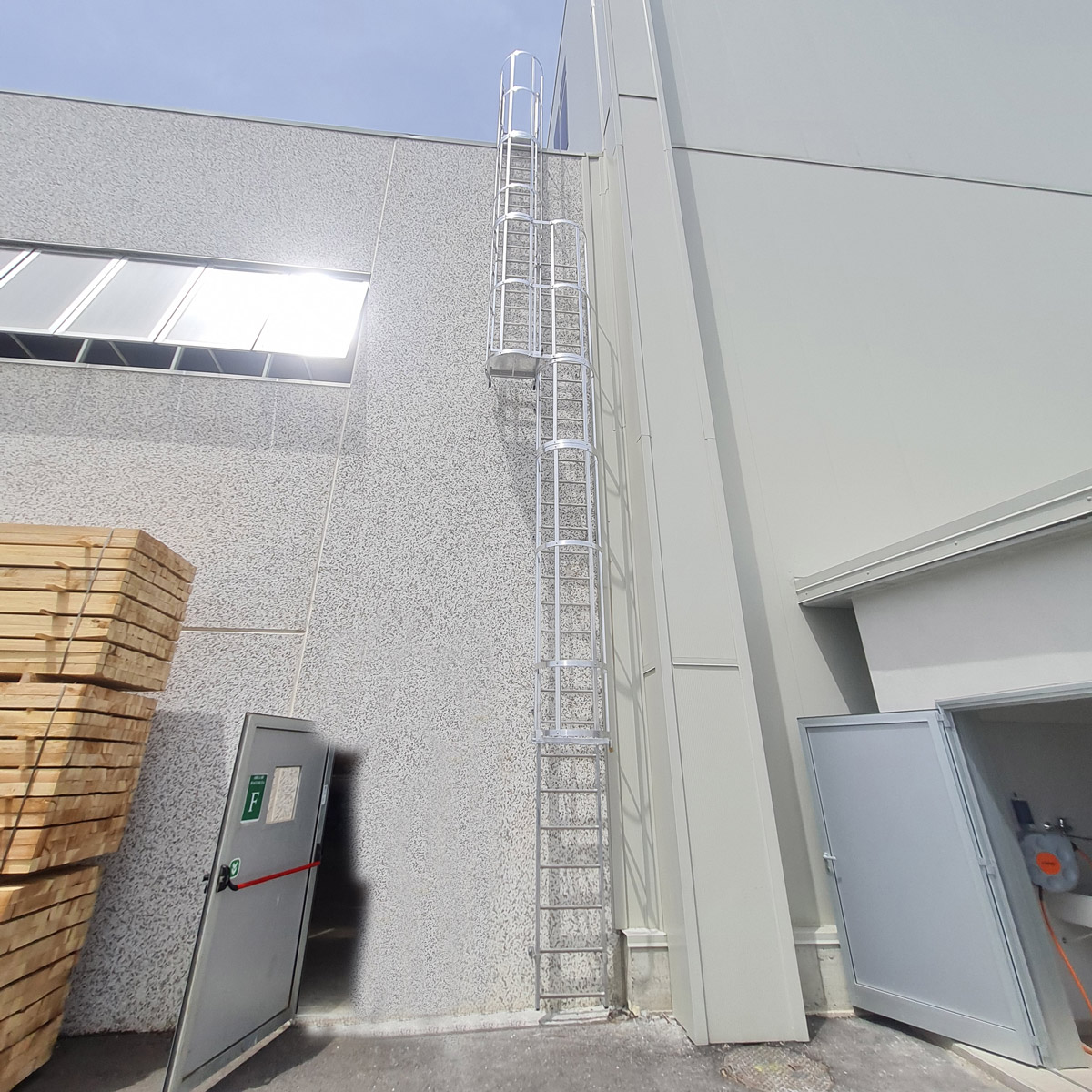 Vægstige med rygbøjle i aluminium, set nedefra, med platform og videre adgang op til taget.